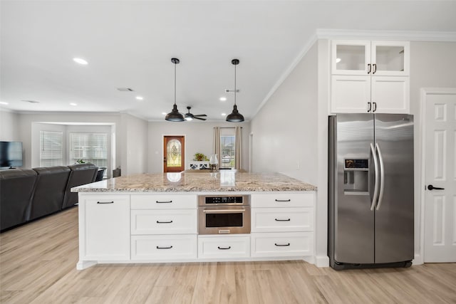 kitchen featuring light stone countertops, appliances with stainless steel finishes, open floor plan, and ornamental molding