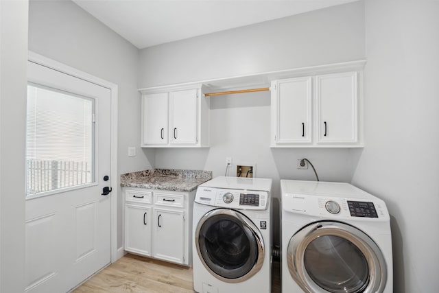 clothes washing area featuring light wood-style flooring, washing machine and clothes dryer, and cabinet space