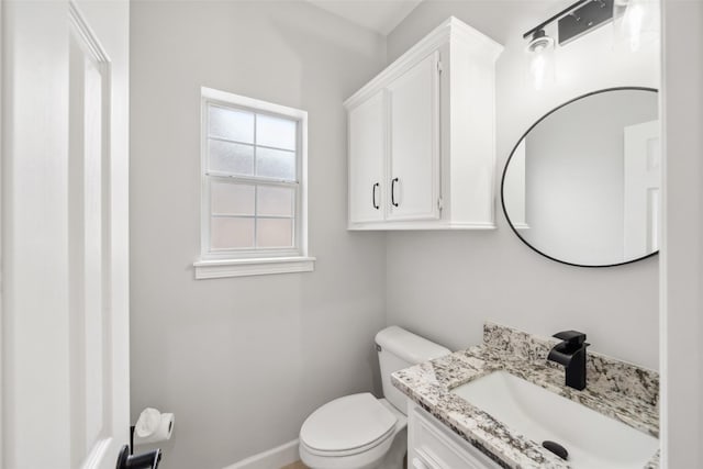 half bath featuring vanity, toilet, and baseboards