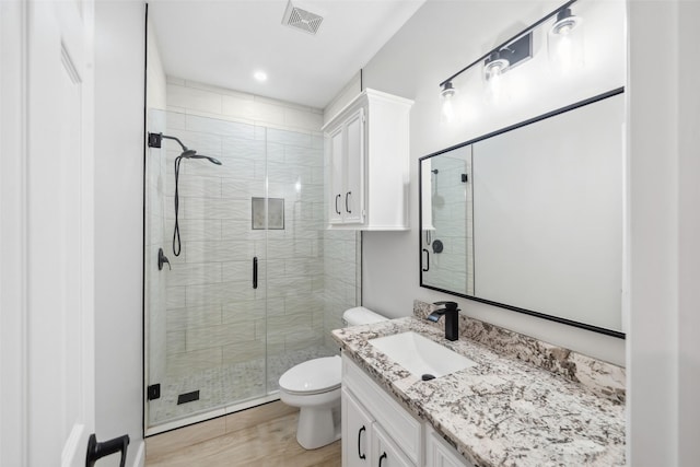 full bathroom featuring toilet, vanity, a shower stall, and visible vents