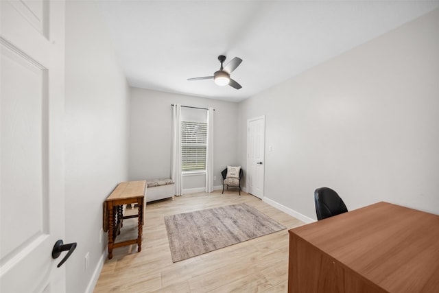 office area with a ceiling fan, light wood-type flooring, and baseboards