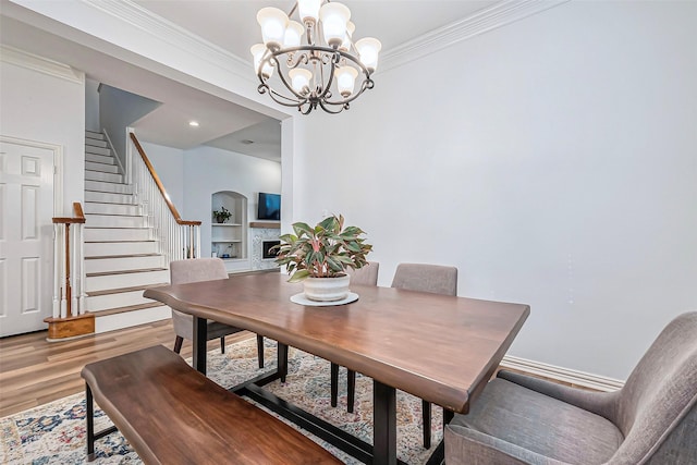 dining room featuring ornamental molding, a fireplace, light wood finished floors, and stairs