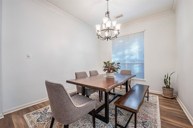 dining area with a notable chandelier, wood finished floors, visible vents, baseboards, and crown molding