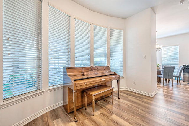 living area with a chandelier, light wood-type flooring, and baseboards