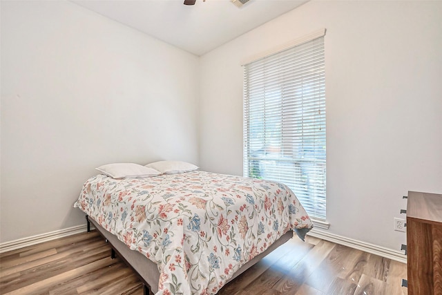 bedroom featuring ceiling fan, visible vents, baseboards, and wood finished floors