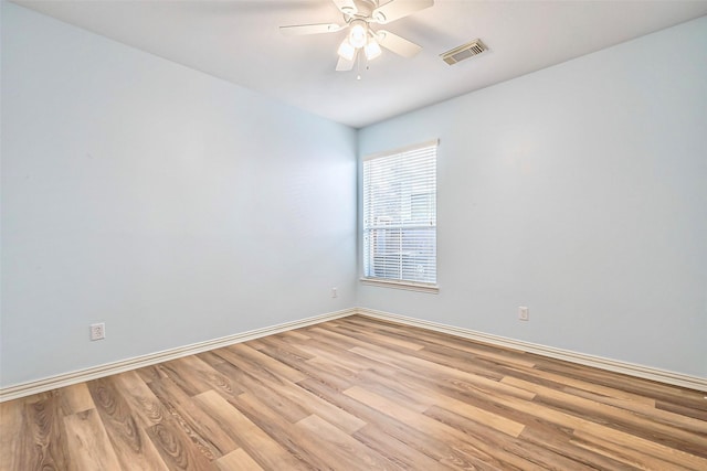 spare room with light wood-style flooring, visible vents, ceiling fan, and baseboards