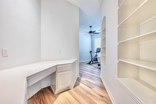 home office featuring a ceiling fan, light wood-type flooring, built in study area, and baseboards