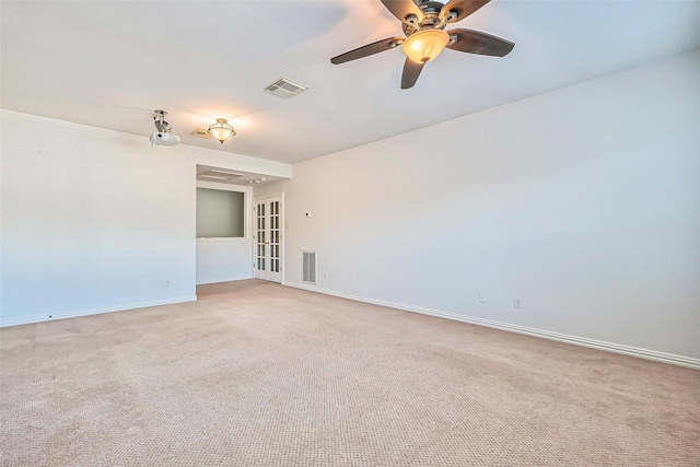 carpeted spare room featuring french doors, a ceiling fan, visible vents, and baseboards