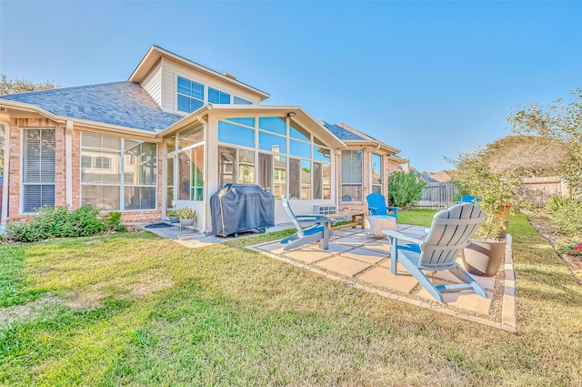 rear view of house featuring a shingled roof, a lawn, a patio, a sunroom, and fence