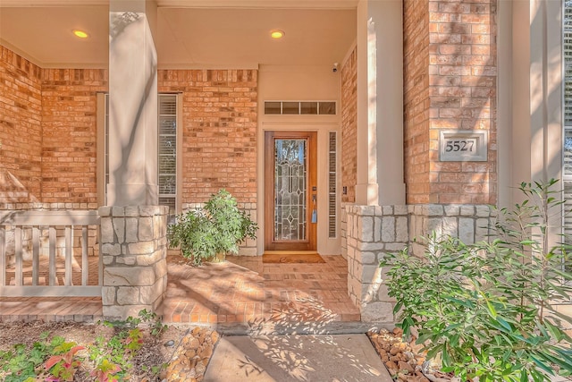 view of exterior entry with covered porch and brick siding