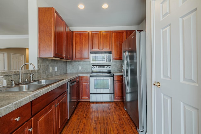 kitchen featuring tasteful backsplash, appliances with stainless steel finishes, dark wood-type flooring, crown molding, and a sink