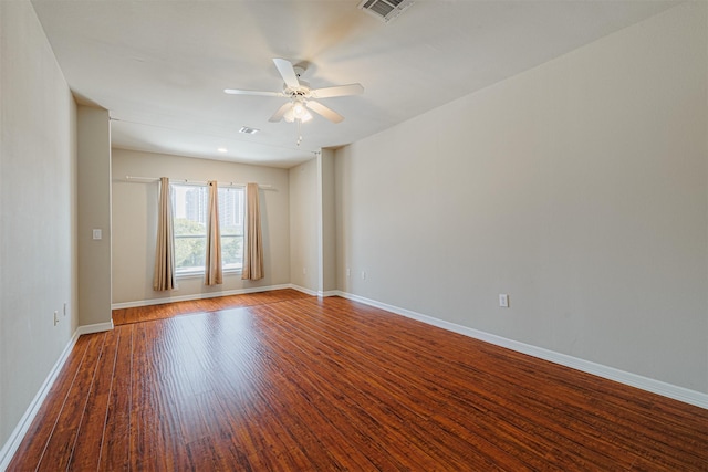 empty room with baseboards, visible vents, ceiling fan, and wood finished floors