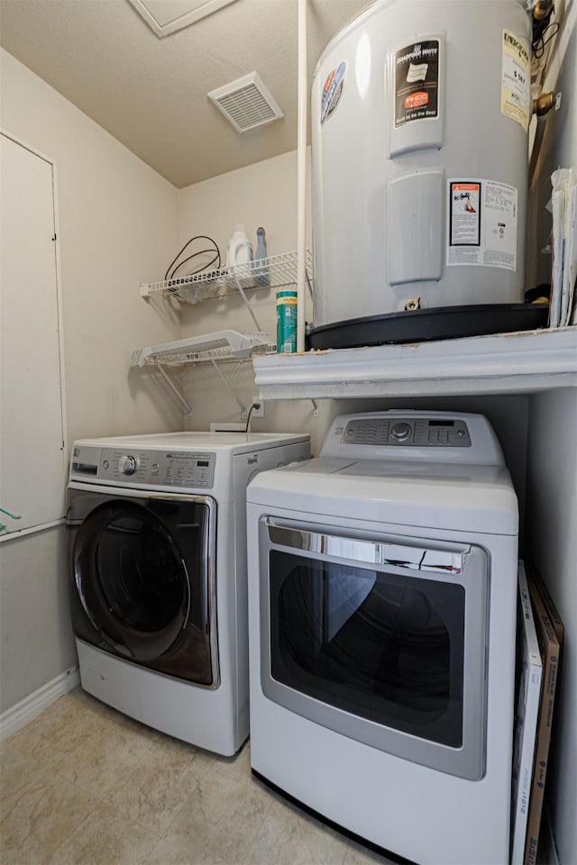 laundry area featuring laundry area, visible vents, baseboards, washing machine and dryer, and water heater