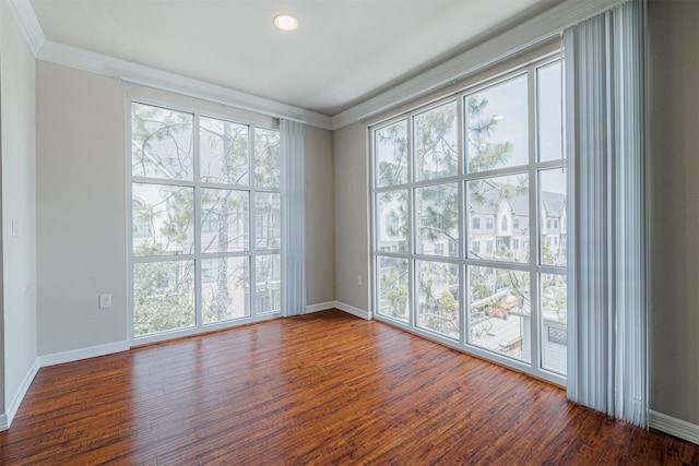 spare room featuring baseboards, wood finished floors, and crown molding