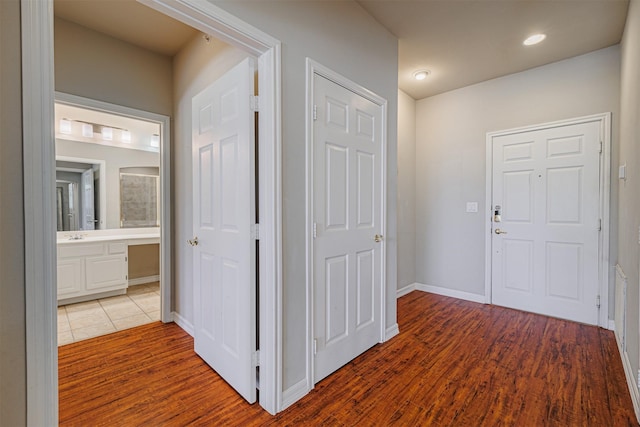 hall featuring baseboards, wood finished floors, and recessed lighting