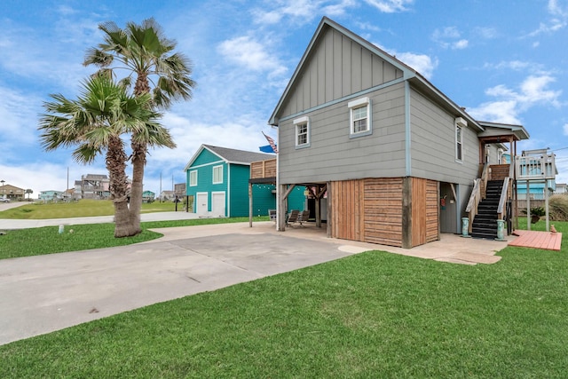 exterior space featuring stairs, a lawn, board and batten siding, and concrete driveway