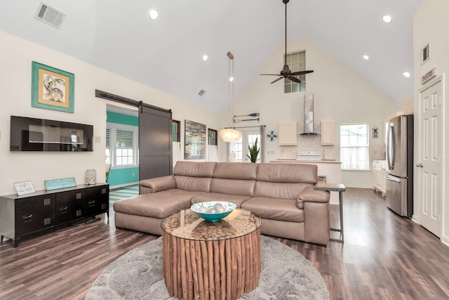 living area featuring high vaulted ceiling, a barn door, dark wood-style flooring, visible vents, and a ceiling fan