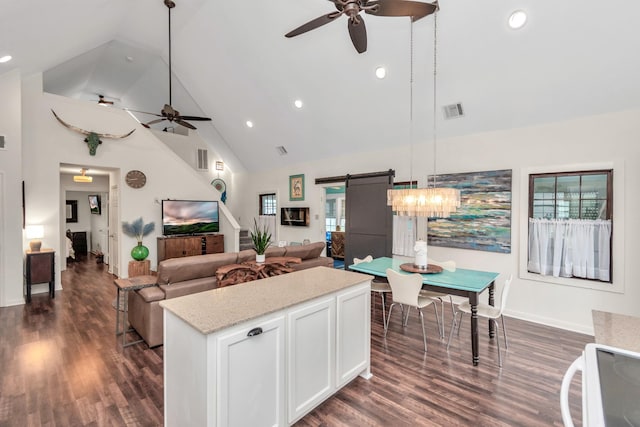 kitchen with a barn door, visible vents, white cabinets, dark wood-style floors, and open floor plan