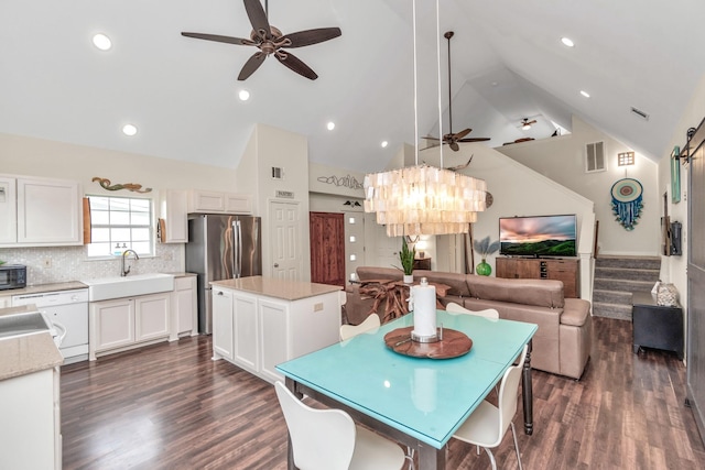 dining space featuring dark wood-type flooring, ceiling fan with notable chandelier, visible vents, and stairs