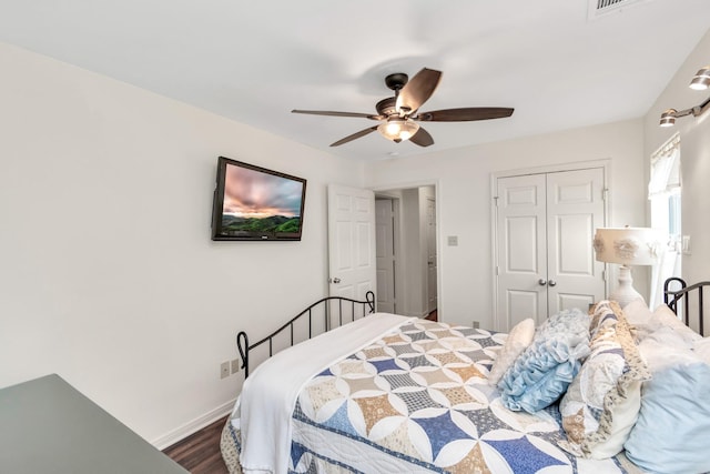 bedroom with ceiling fan, a closet, dark wood finished floors, and baseboards