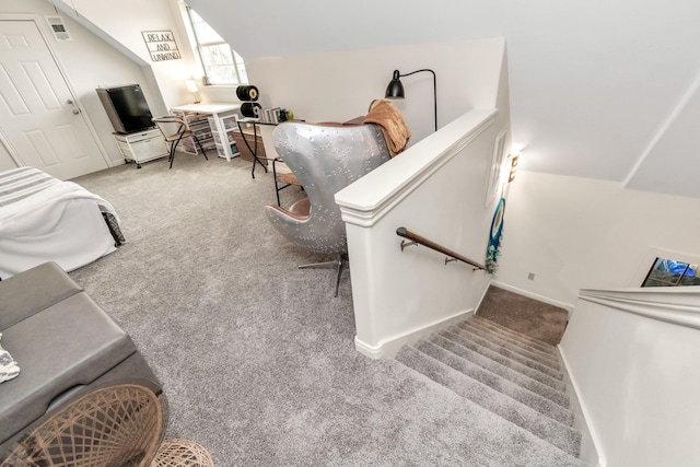 carpeted living area with lofted ceiling, visible vents, and baseboards