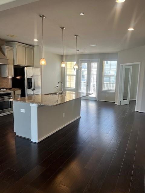 kitchen with stainless steel appliances, light stone counters, a sink, and dark wood finished floors