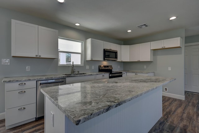 kitchen with a center island, stainless steel appliances, visible vents, white cabinetry, and a sink