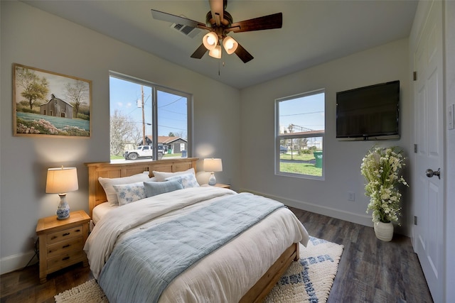 bedroom with ceiling fan, wood finished floors, visible vents, and baseboards