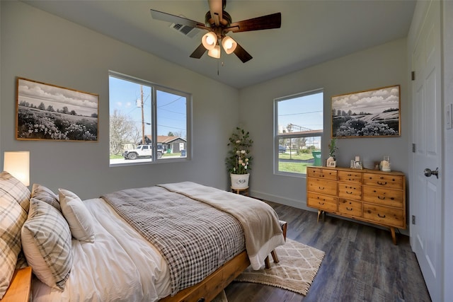 bedroom featuring a ceiling fan, wood finished floors, visible vents, and baseboards