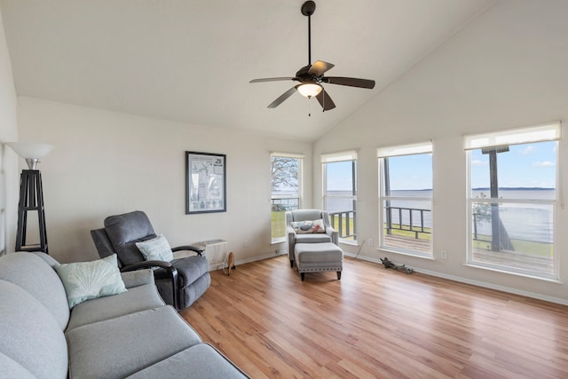 living room with light wood-style floors, ceiling fan, high vaulted ceiling, and baseboards