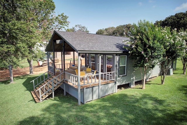 rear view of property with a yard, a wooden deck, central AC, and roof with shingles