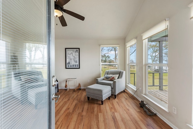 living area featuring vaulted ceiling, light wood-style flooring, and baseboards