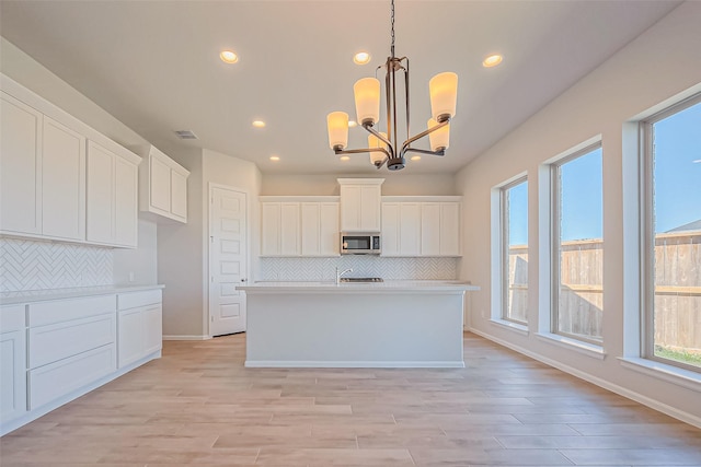 4046 Colony Ln, Missouri City, TX 77459 - kitchen with white cabinetry, stainless steel microwave, an inviting chandelier, and tasteful backsplash
