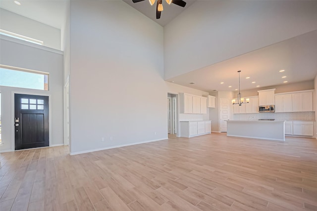 4046 Colony Ln, Missouri City, TX 77459 - unfurnished living room with recessed lighting, light wood finished floors, ceiling fan with notable chandelier, and a towering ceiling