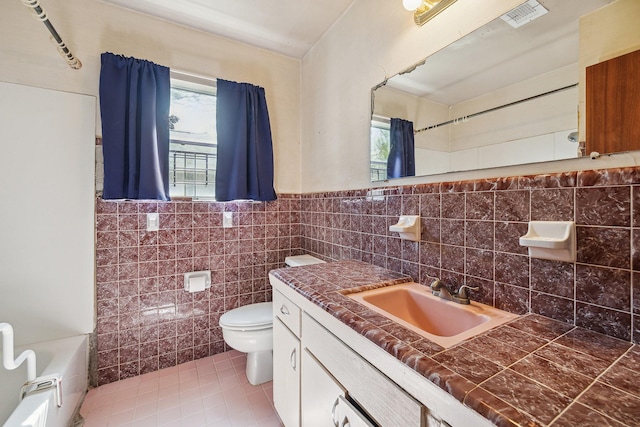 bathroom with plenty of natural light, visible vents, a sink, and tile walls