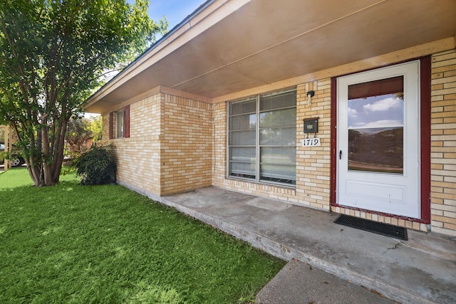 property entrance featuring brick siding and a yard