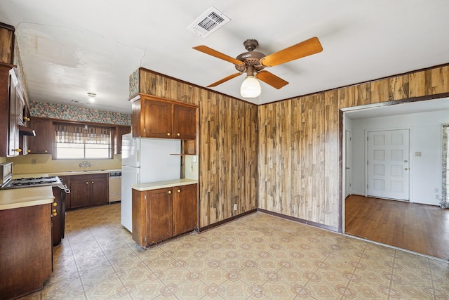 kitchen featuring dishwashing machine, light countertops, visible vents, and wooden walls