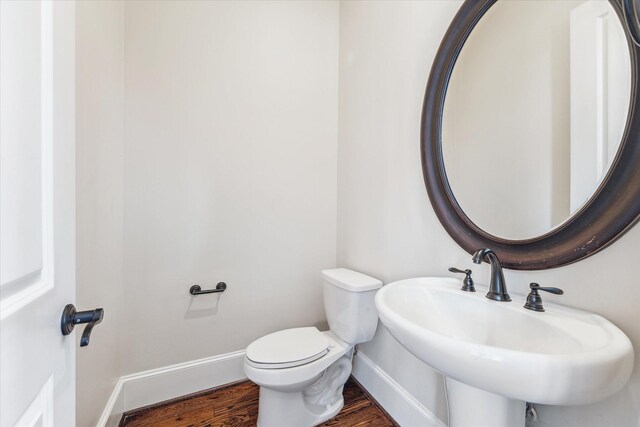 bathroom with toilet, a sink, baseboards, and wood finished floors