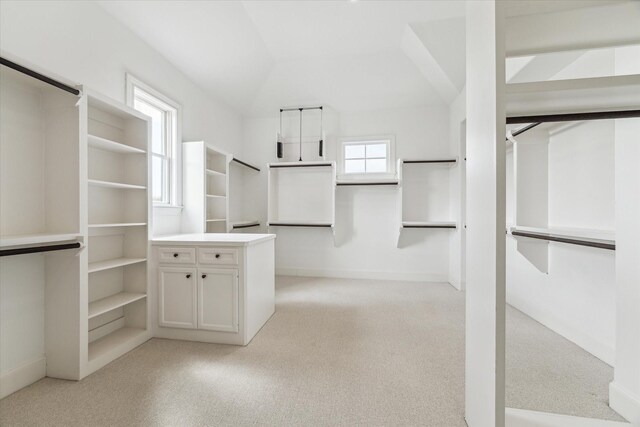 walk in closet featuring light carpet and vaulted ceiling