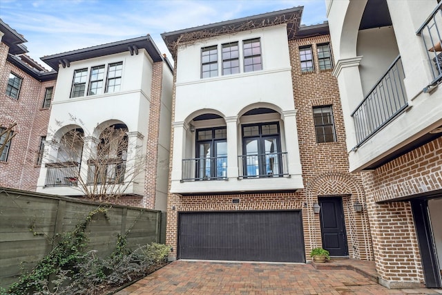 view of front of property featuring stucco siding, decorative driveway, and brick siding