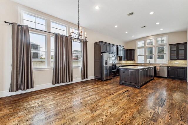 kitchen featuring dark brown cabinetry, stainless steel appliances, visible vents, tasteful backsplash, and dark wood finished floors