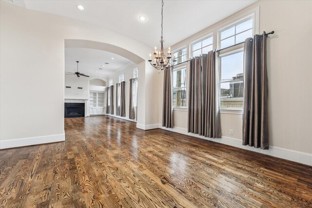 unfurnished living room with ceiling fan with notable chandelier, a fireplace, wood finished floors, and baseboards