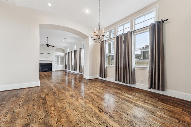 interior space with a fireplace, ceiling fan with notable chandelier, wood finished floors, and baseboards