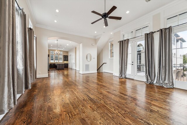 unfurnished living room featuring arched walkways, ornamental molding, and dark wood-type flooring