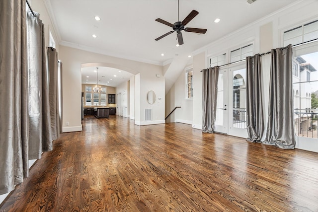 unfurnished living room featuring visible vents, arched walkways, dark wood-style flooring, and crown molding