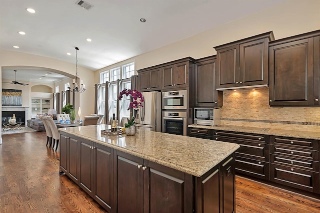 kitchen featuring a fireplace, dark wood-type flooring, arched walkways, and stainless steel fridge