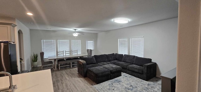 living area featuring recessed lighting, arched walkways, a ceiling fan, and light wood finished floors