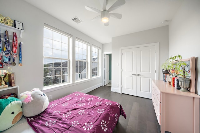 bedroom with baseboards, visible vents, a ceiling fan, dark wood finished floors, and a closet