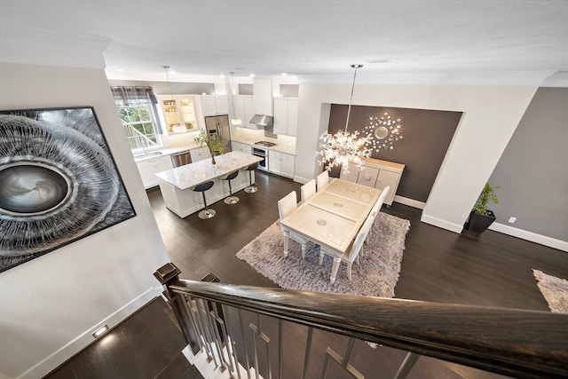 living room featuring an inviting chandelier, baseboards, dark wood-style floors, and ornamental molding