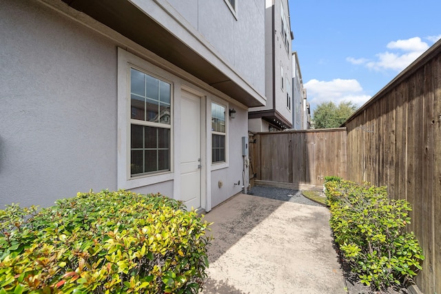 property entrance with a patio area, fence, and stucco siding